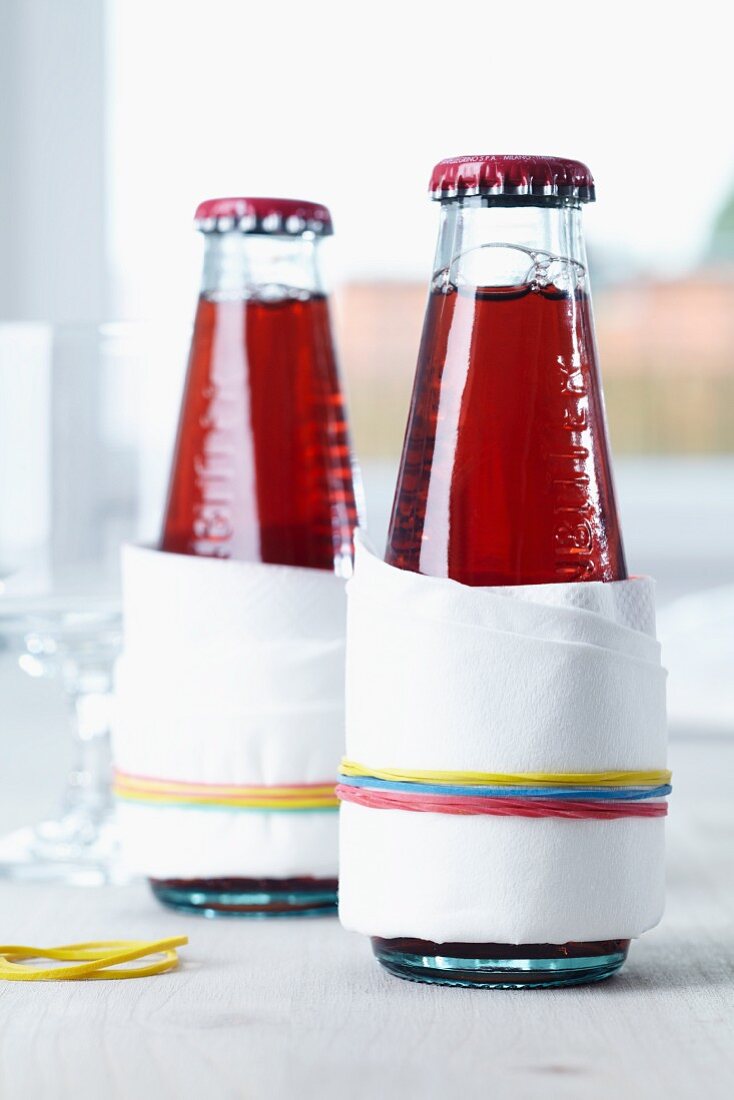 Drip catchers on drinks bottles; paper napkins held in place with rubber bands