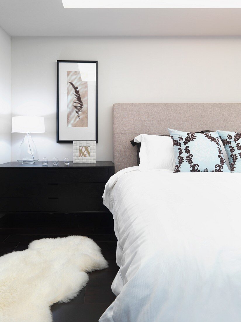 Double bed with headboard and animal-skin rug on floor of bedroom