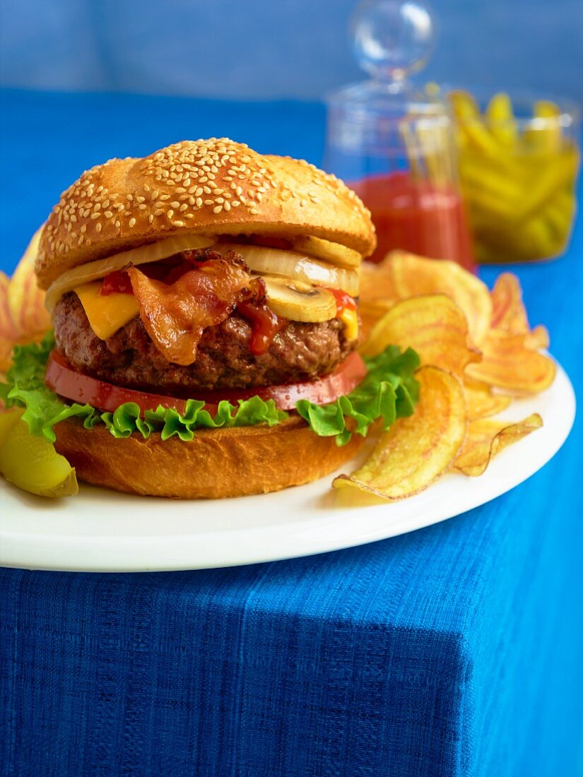 Bacon Cheeseburger with Mushrooms, Onions, Lettuce and Tomato; Potato Chips and a Pickle