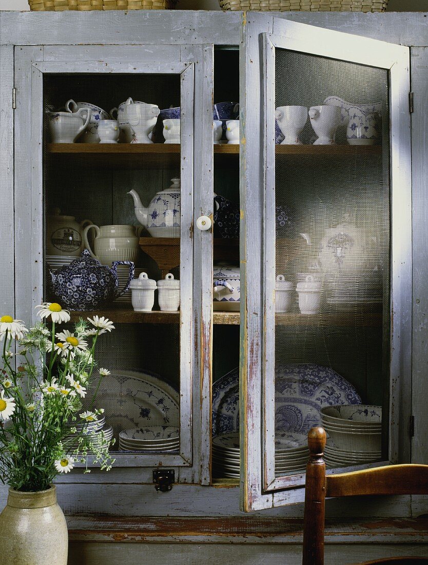 Vintage-style display cabinet with collection of blue and white crockery