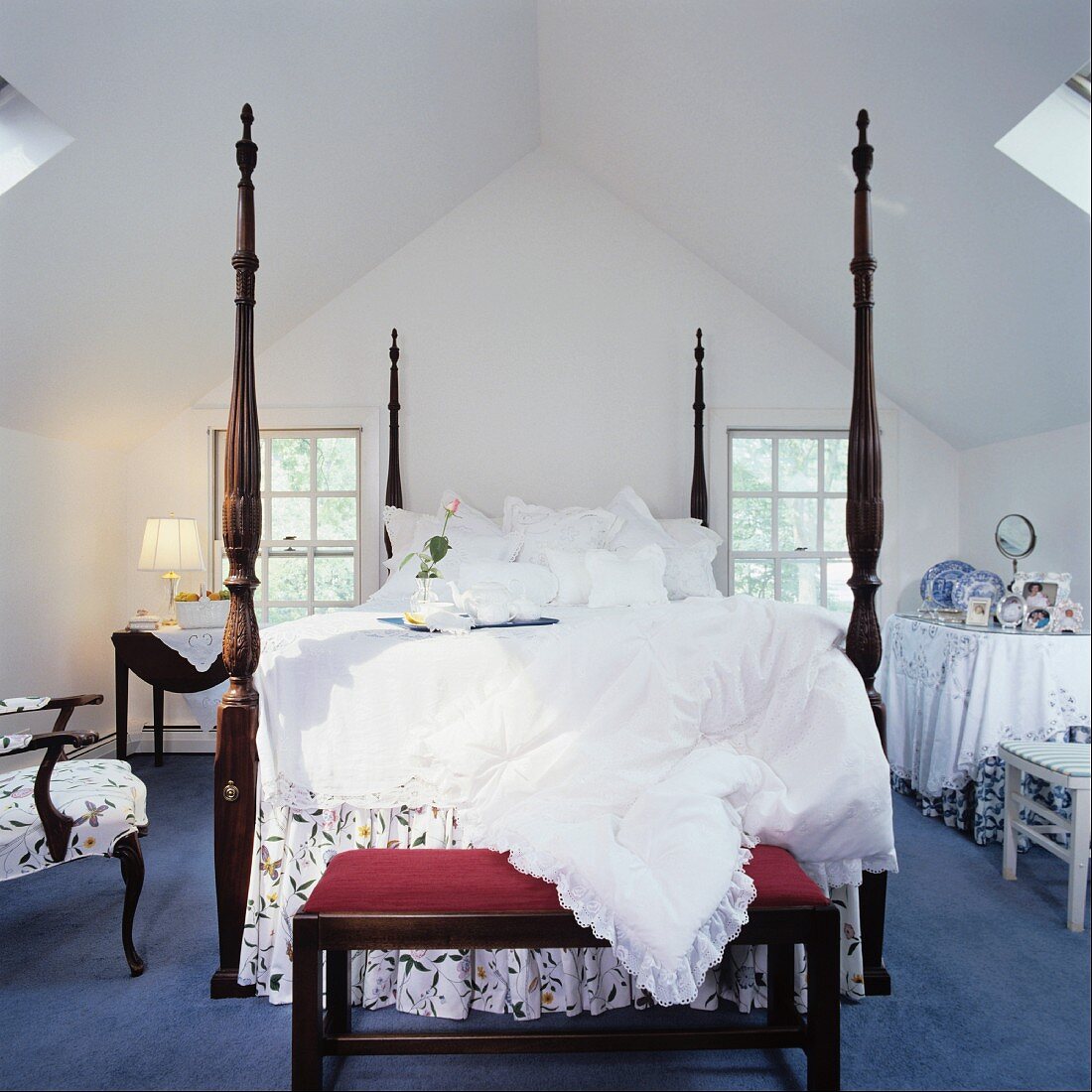 Grand bed with high bedposts and ottoman in attic bedroom