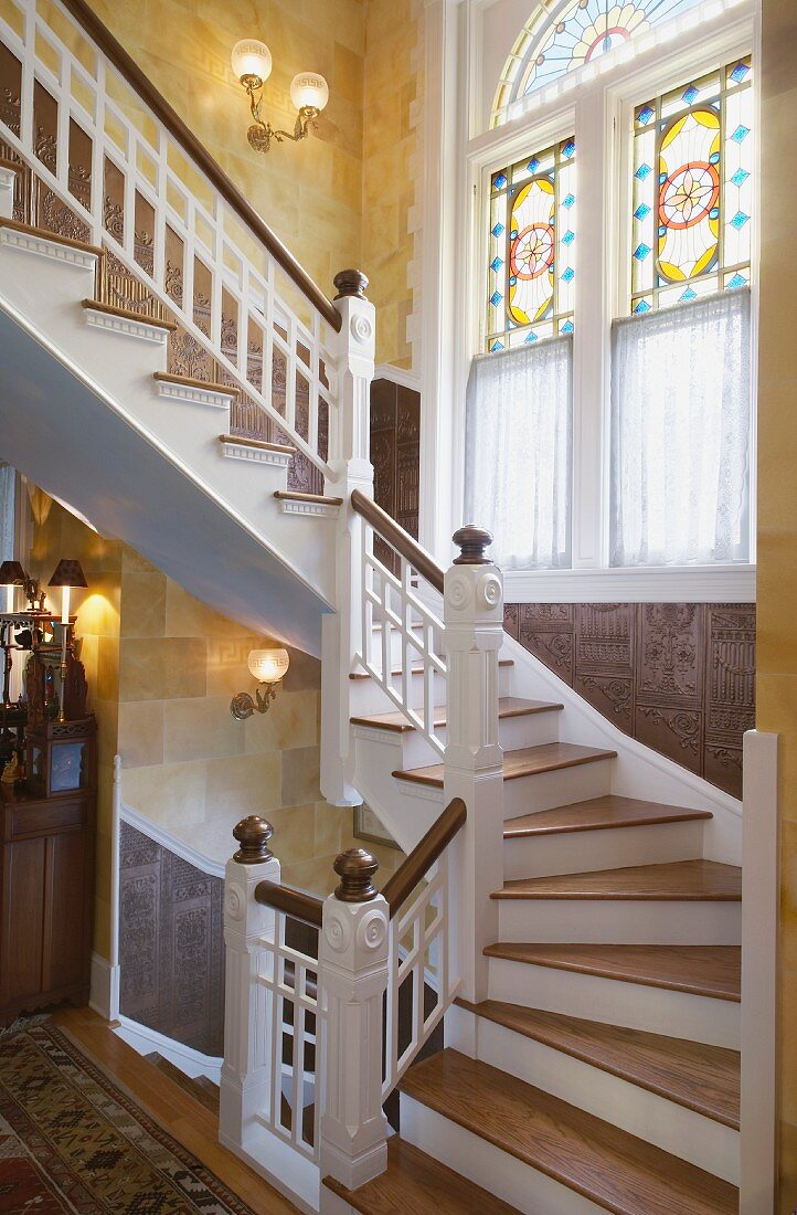 Grand staircase with ornate stained and leaded glass windows and carved wood panelling on walls