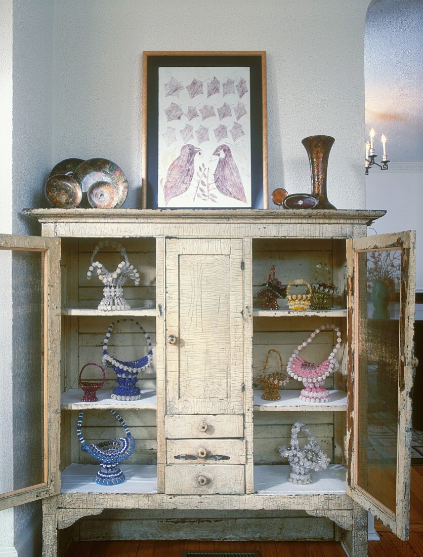 Vintage display cabinet with collection of baskets and framed picture of birds