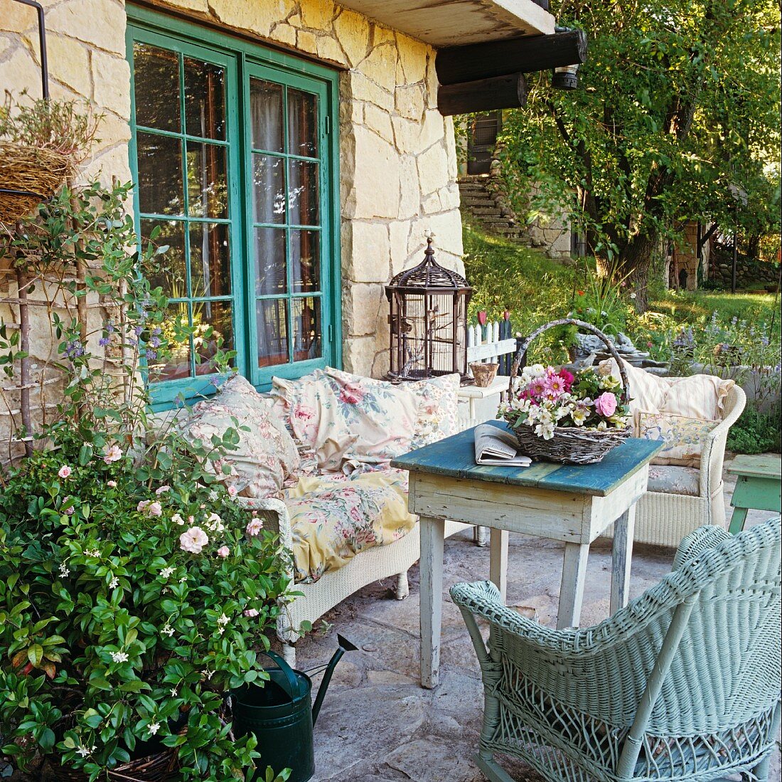 Garden terrace of stone house with vintage furniture and decorative flower arrangement in basket