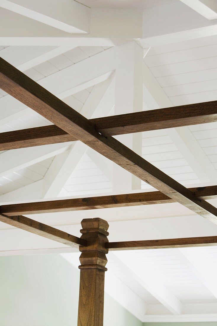 Detail of wooden bed posts and white ceiling beams