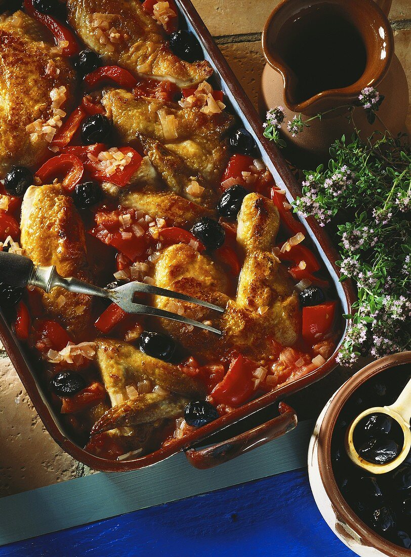 Portioned chicken with black olives, pieces of red pepper