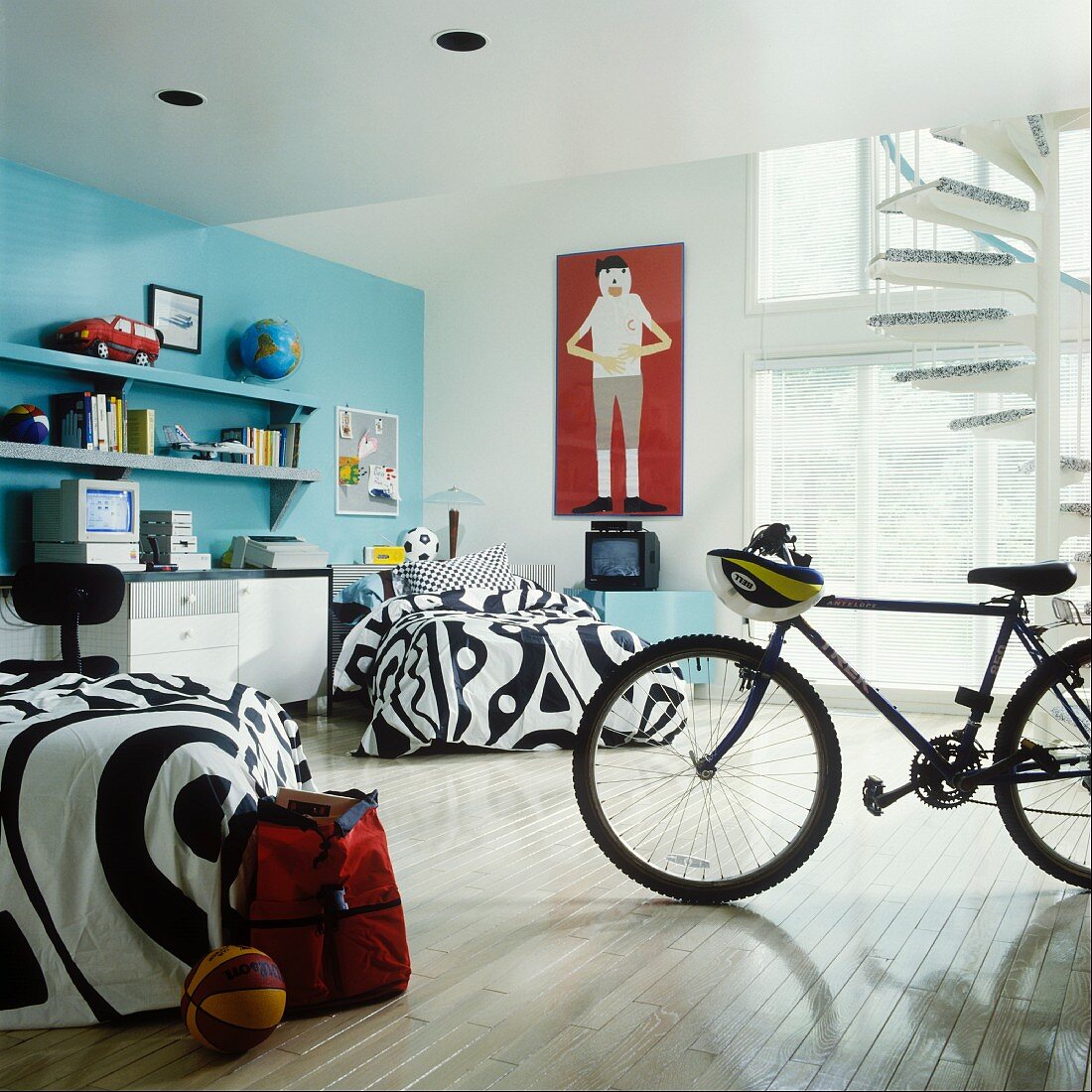 Jungenzimmer mit blauer Wand, schwarz-weisser Bettwäsche, Schreibtisch und Fahrrad