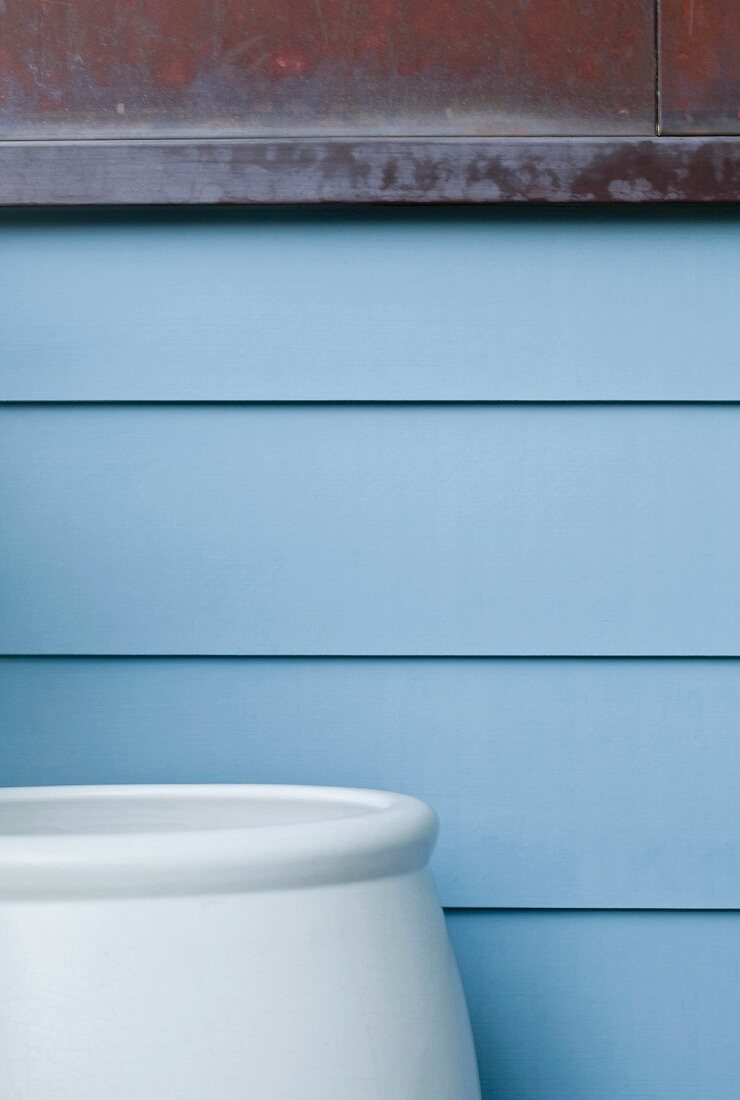 Large blue pot against blue sided home