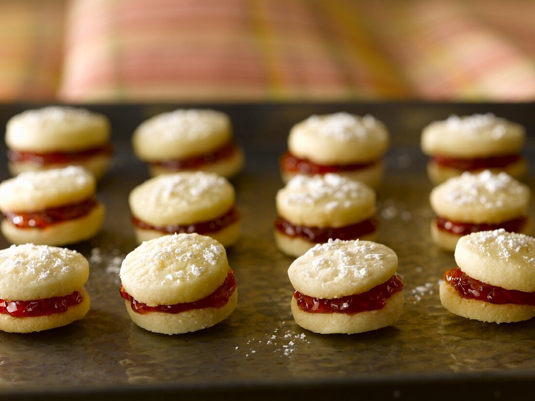 Strawberry Jam Filled Shortbread Cookies Dusted with Powdered Sugar on a Sheet Pan