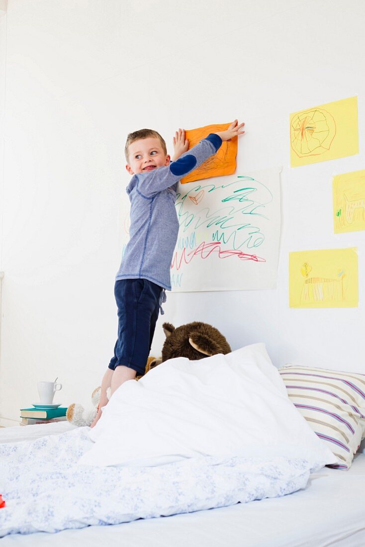 Junge hängt seine Zeichnung an die Wand