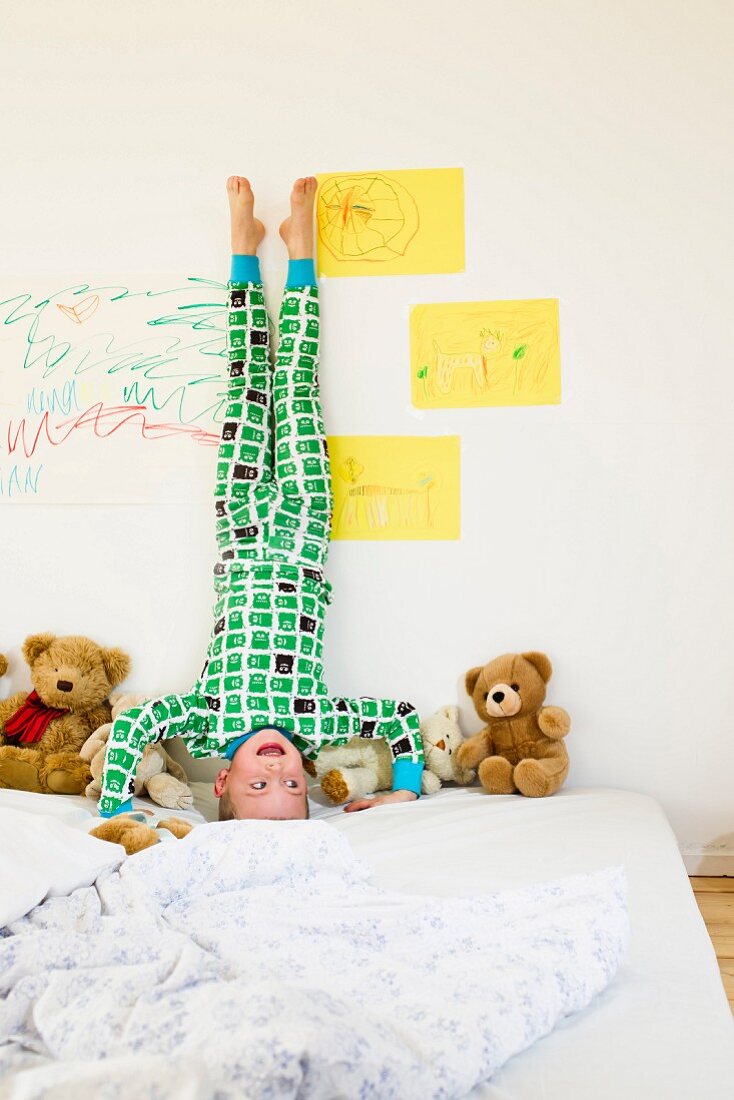 Boy doing headstand on bed