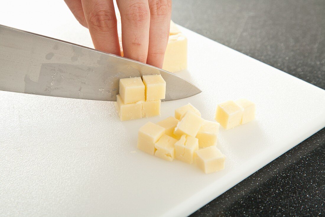 Hands Cutting Cheddar Cheese Into Cubes
