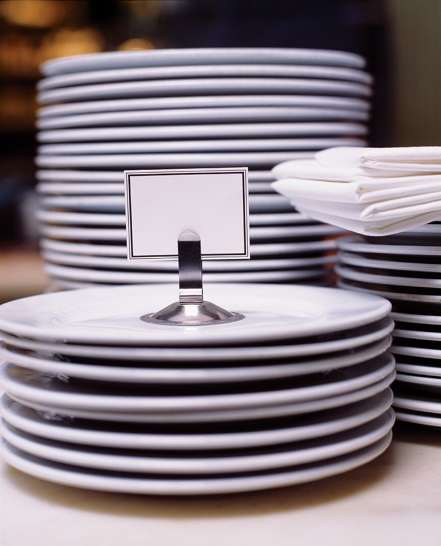 Stacks of Plain White Plates; White Linen Napkins and a Blank Place Card