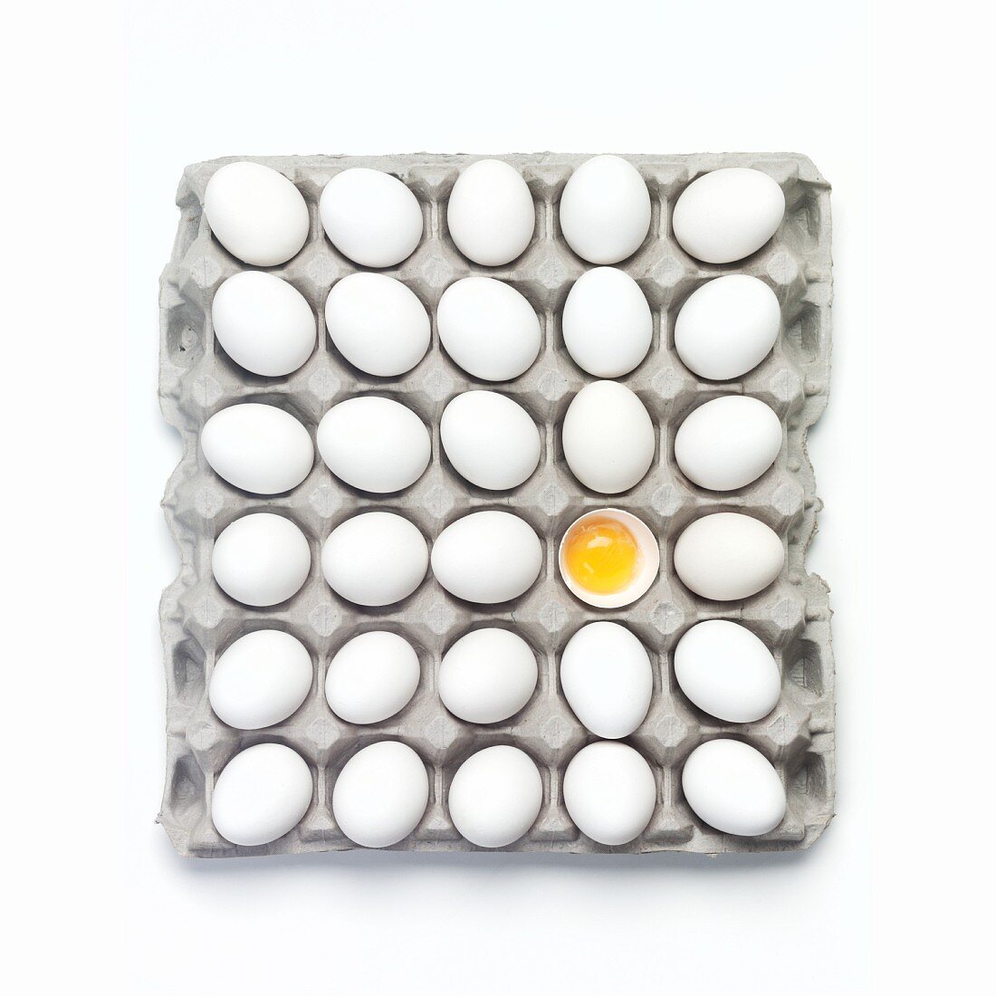 Eier im Eierkarton (eines davon aufgeschlagen)