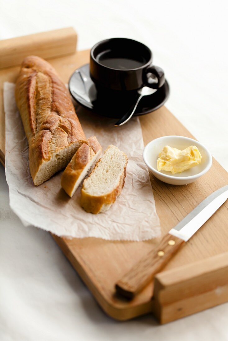 Partially Slices Baguette with Butter and a Cup of Coffee