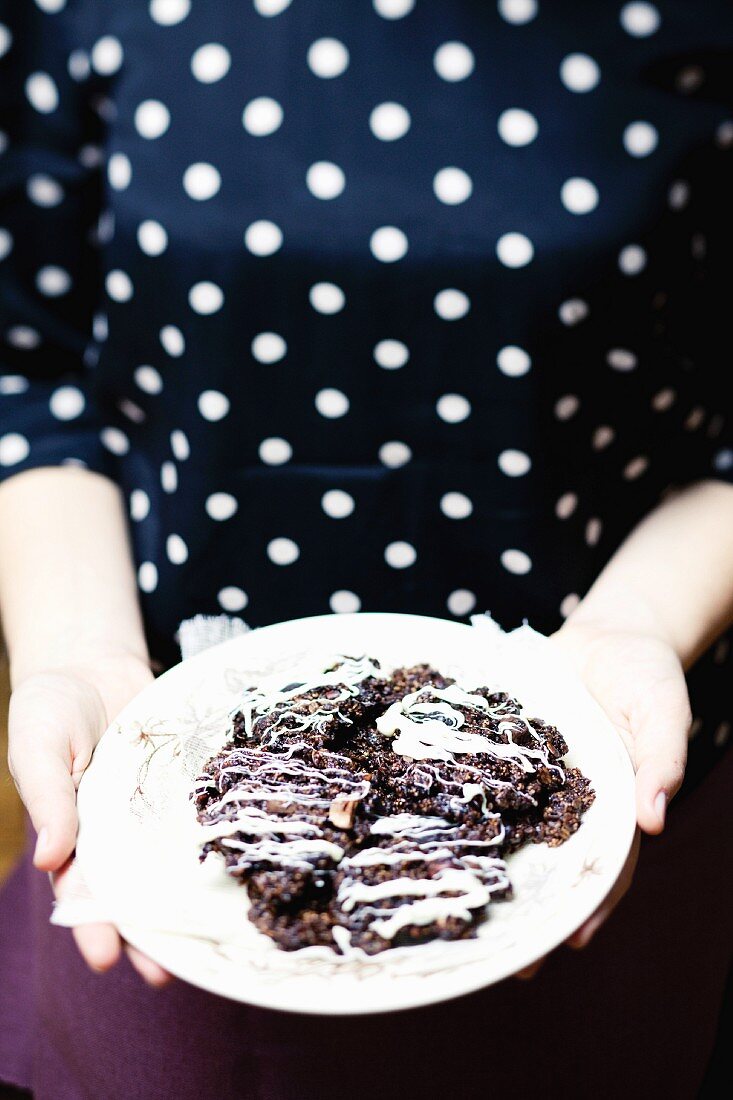 A woman holding a plate of chocolate and hazelnut biscuits