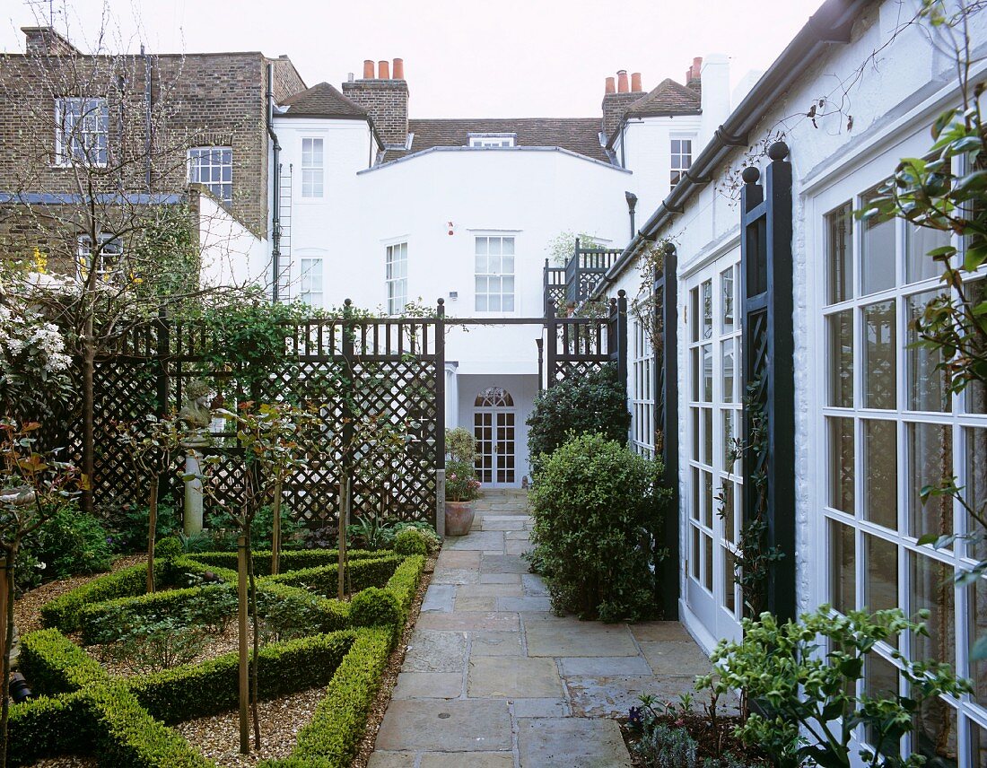 Landscaped city garden in front of bungalow with lattice window doors and view of neighbouring houses