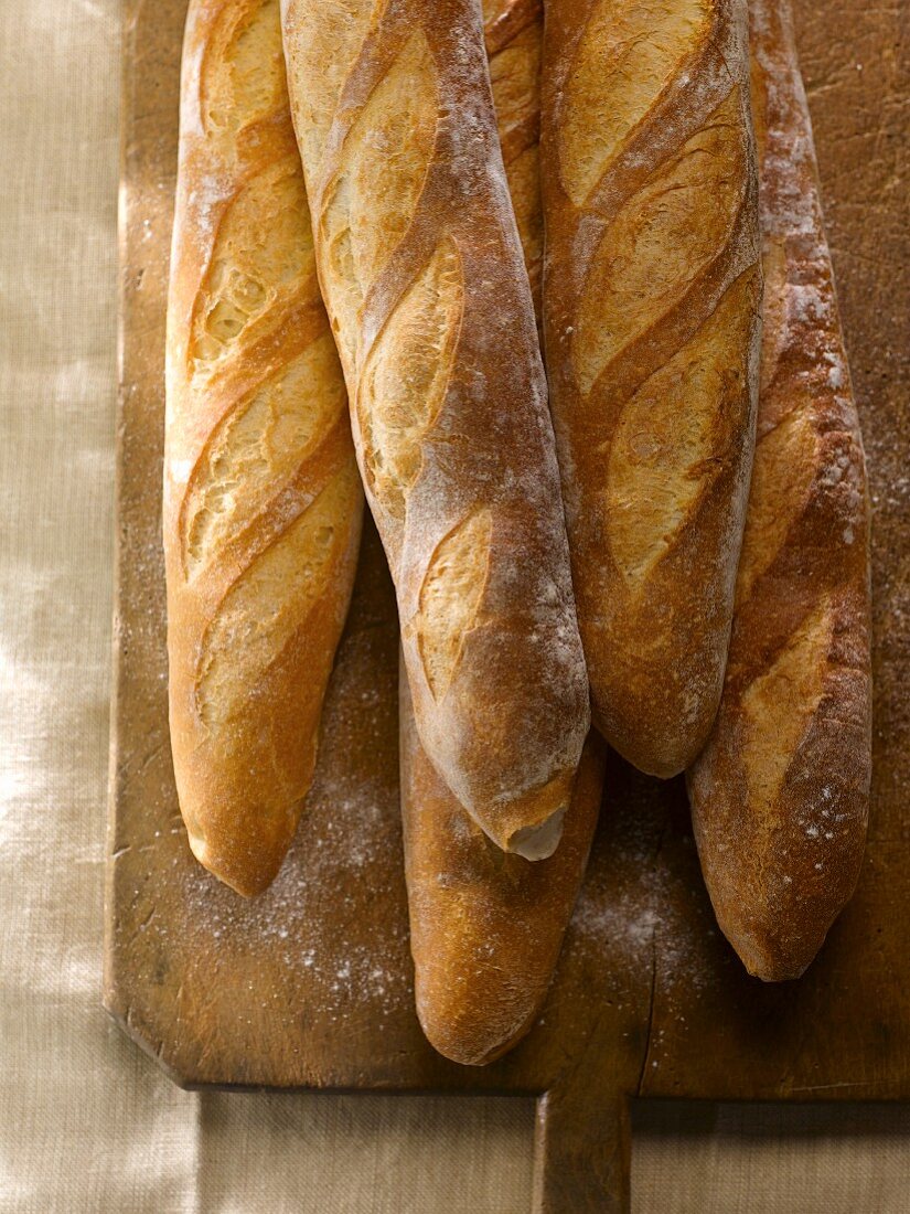 Five Baguettes on a Wooden Cutting Board Sprinkled with Flour