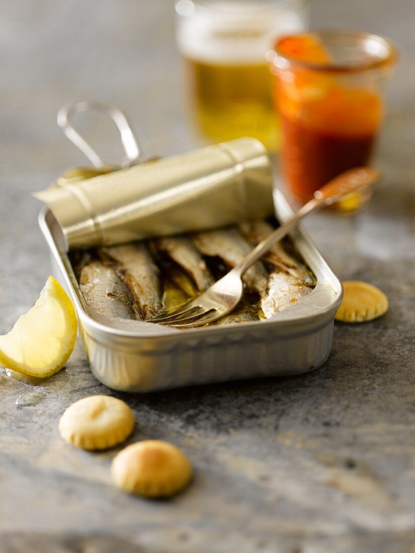 Open Can of Sardines with a Cocktail Fork; Oyster Crackers and Cocktail Sauce; Beer