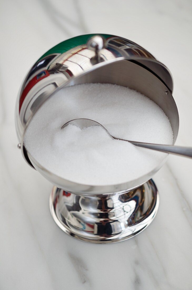 Zuckerbehälter mit Löffel auf Marmortisch