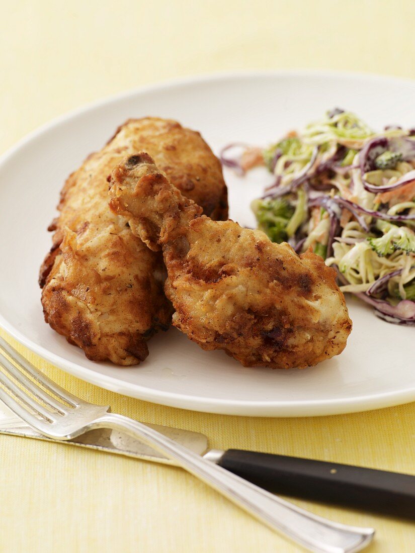 Fried Chicken with Cold Slaw on a White Plate; Fork and Knife