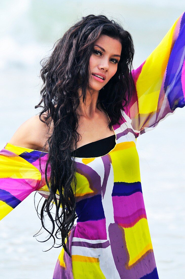 A woman on a beach wearing a brightly patterned dress