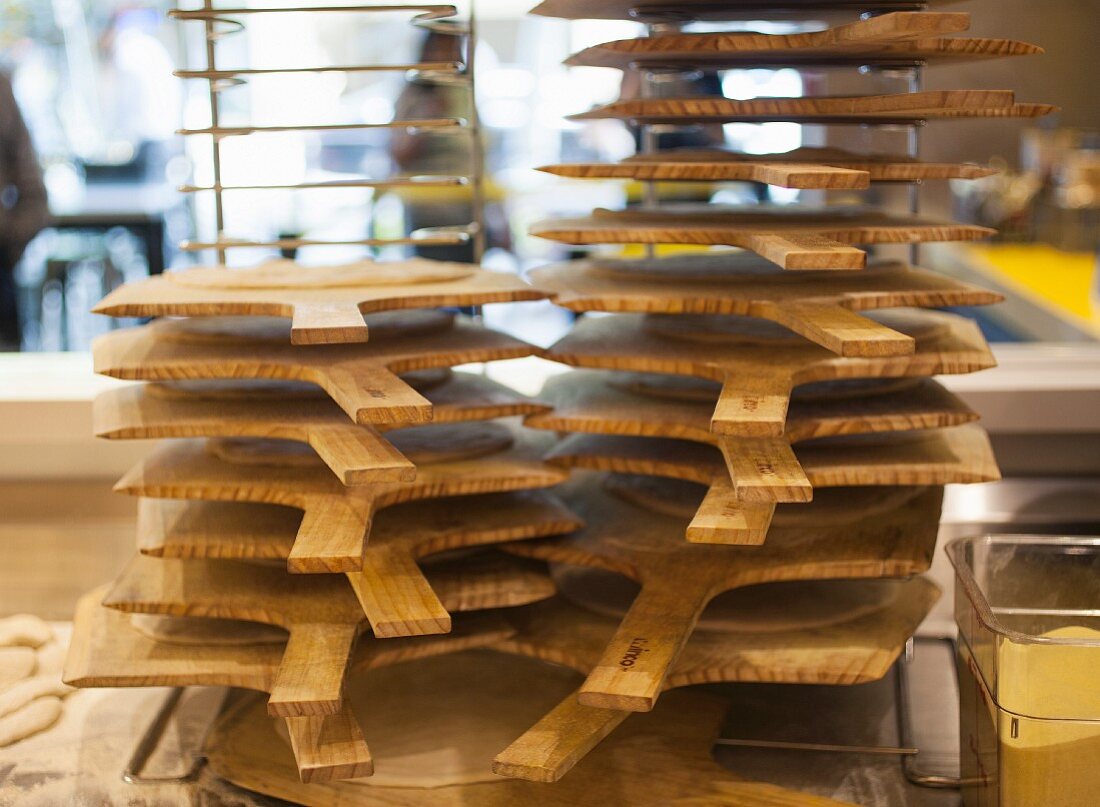 A stack of pizza boards on a rack in a pizzaria