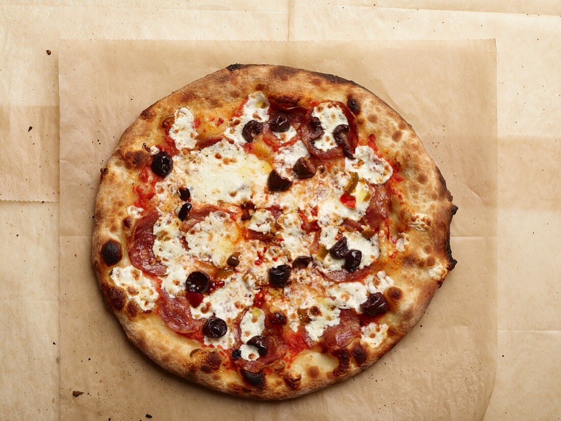 A salami, olive and mozzarella pizza baked in a wood-fired oven (seen from above)