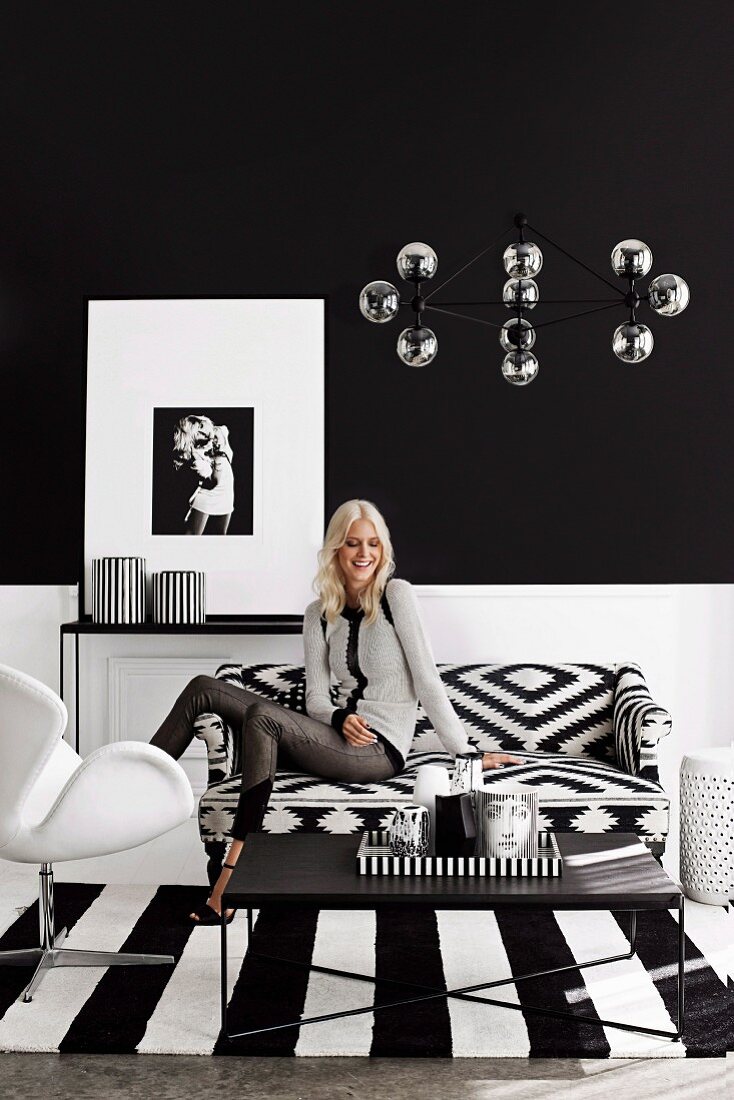 Young woman in a black and white living room with graphic patterns