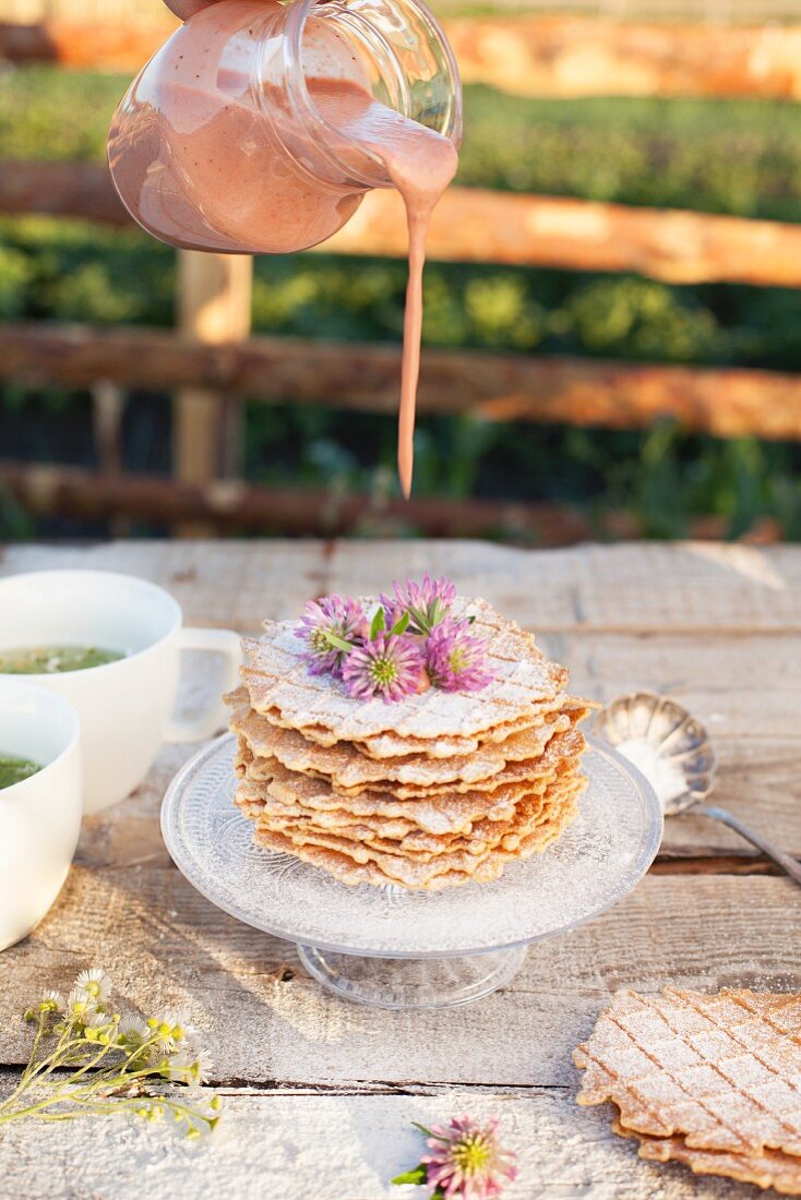 A stack of nut waffles with chamomile tea on a garden table