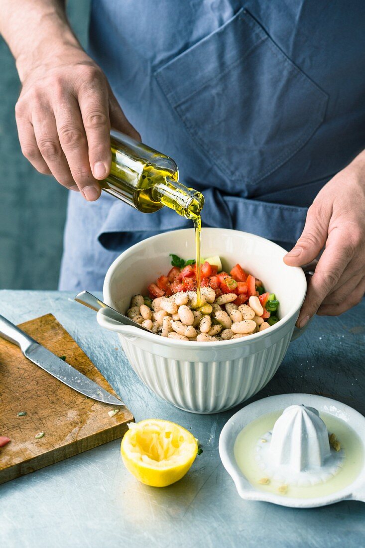 White beans and vegetables being marinated in olive oil