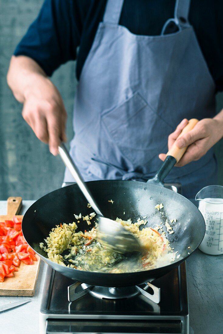 Zwiebeln, Ingwer, Knoblauch und Chili im Wok andünsten