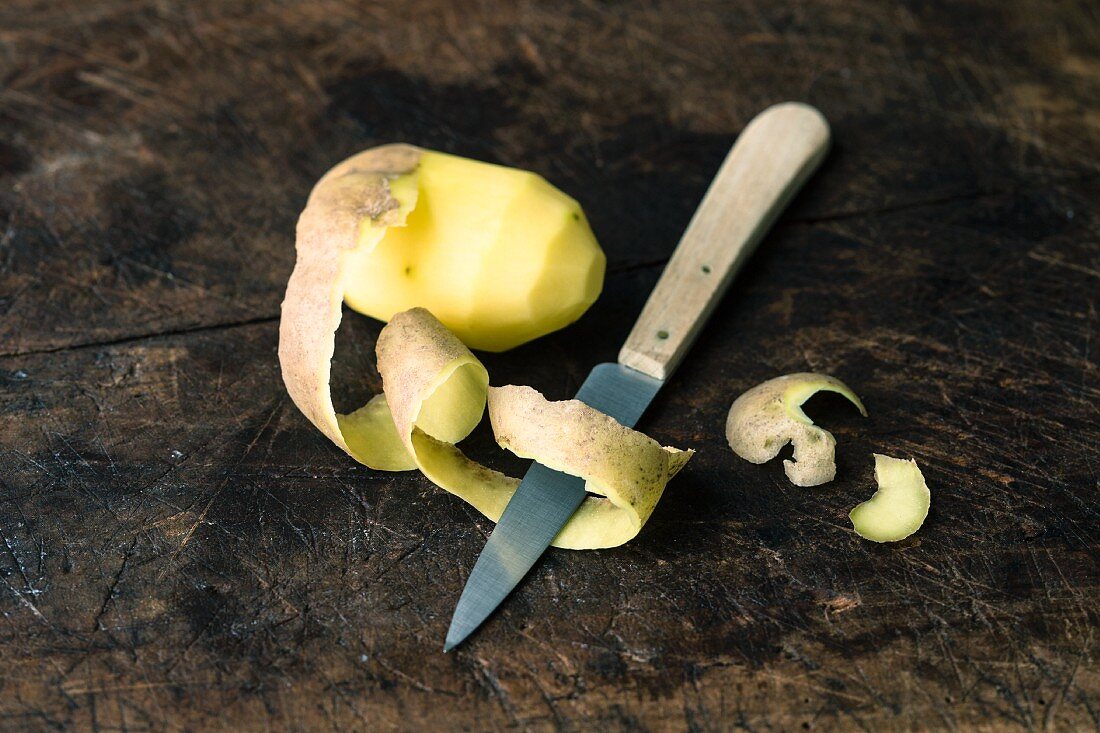 A half-peeled, raw potato