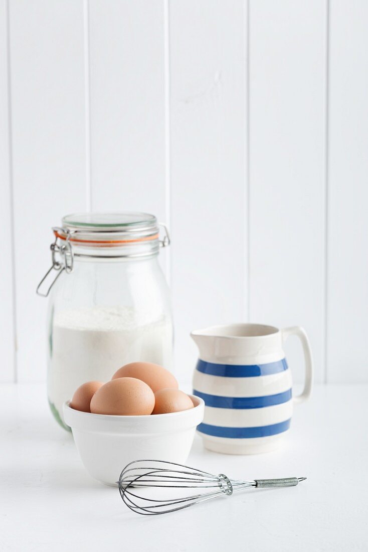 Eier, Mehl, Milchkrug und Schneebesen