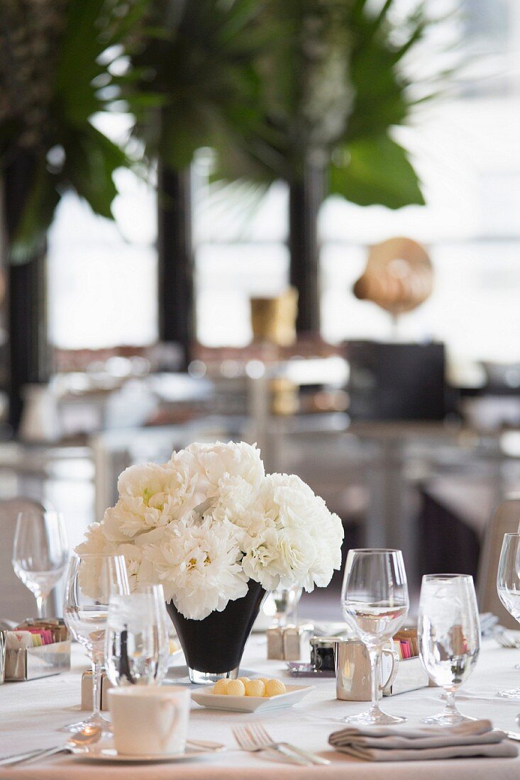 Weiß gedeckter Hochzeitstisch mit weißem Blumenstrauss