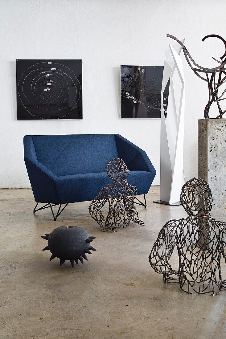 Angular designer sofa surrounded by modern artworks in interior with polished concrete floor