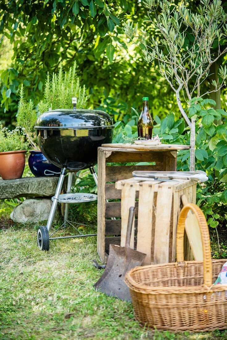 A wooden charcoal grill, wooden boxes and a basket in a garden