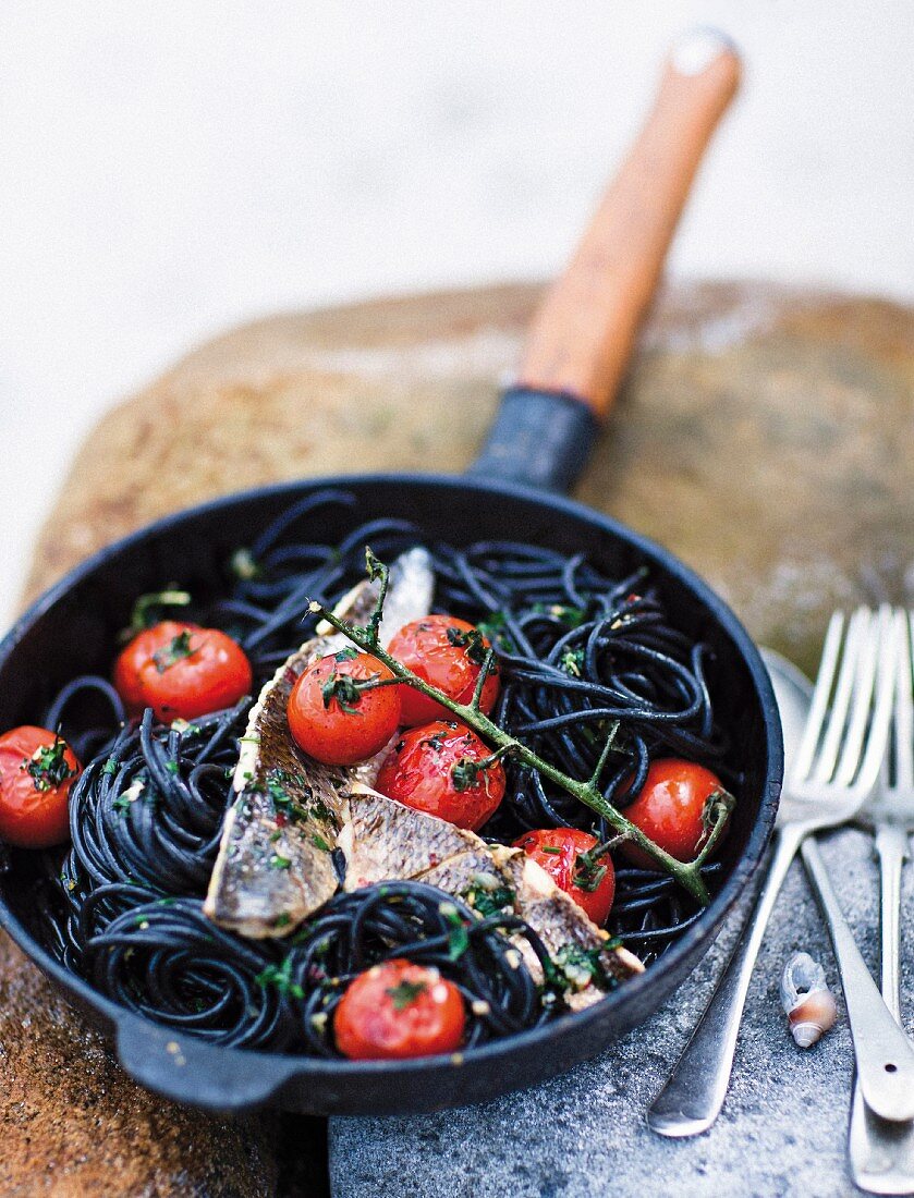 Fish fillet with vine tomatoes on squid spaghetti