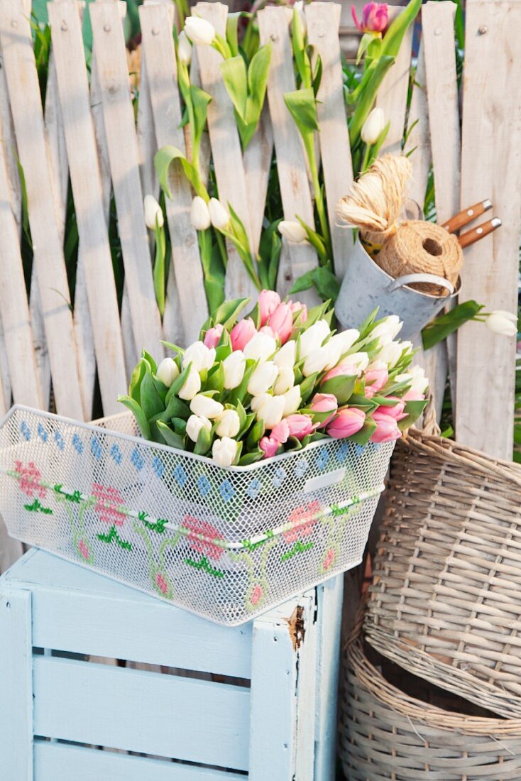 Bestickter Fahrradkorb mit Tulpen auf hellblau gestrichener Holzkiste