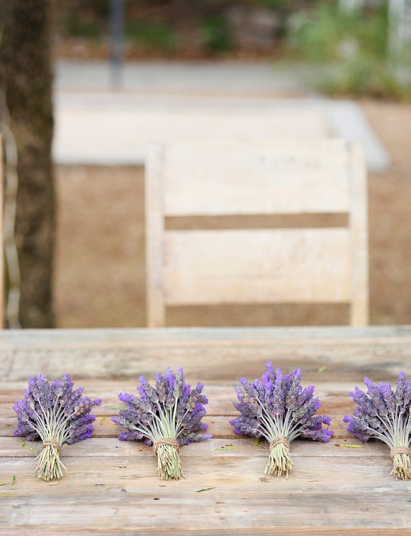 Mehrere Lavendelsträusschen auf Holztisch im Garten