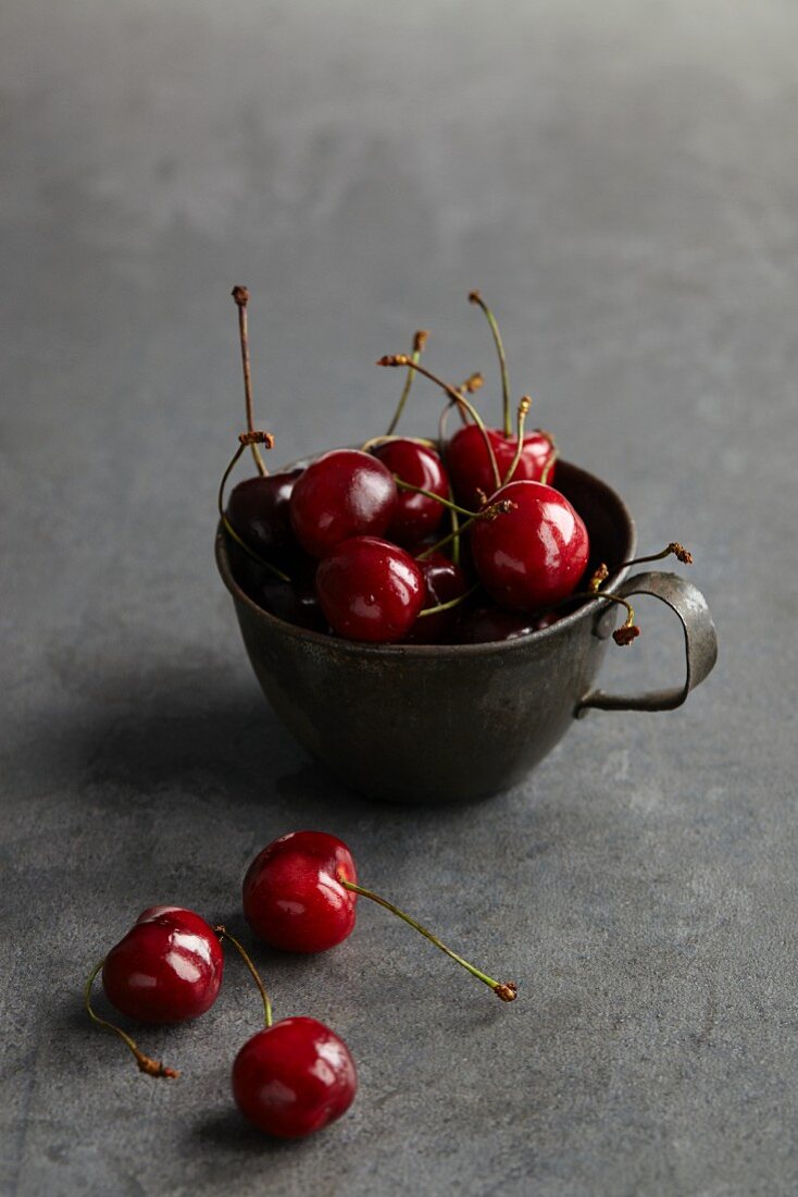 Red cherries in an old metal cup