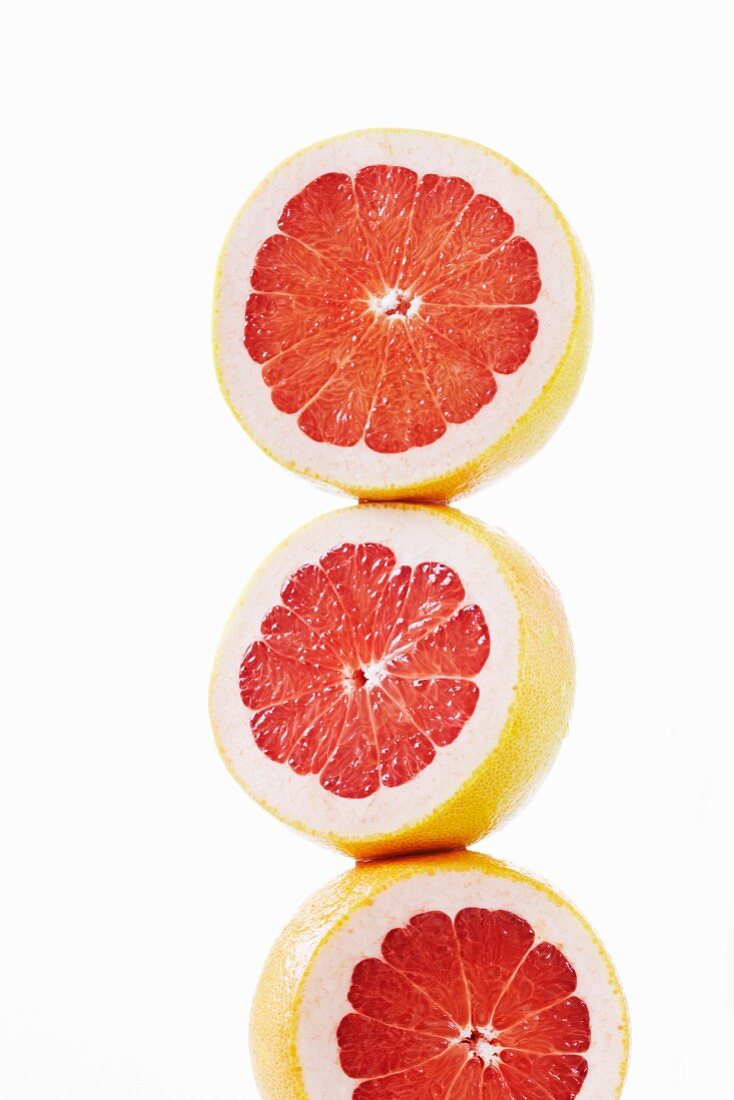 Three pink grapefruit halves stacked on top of each other