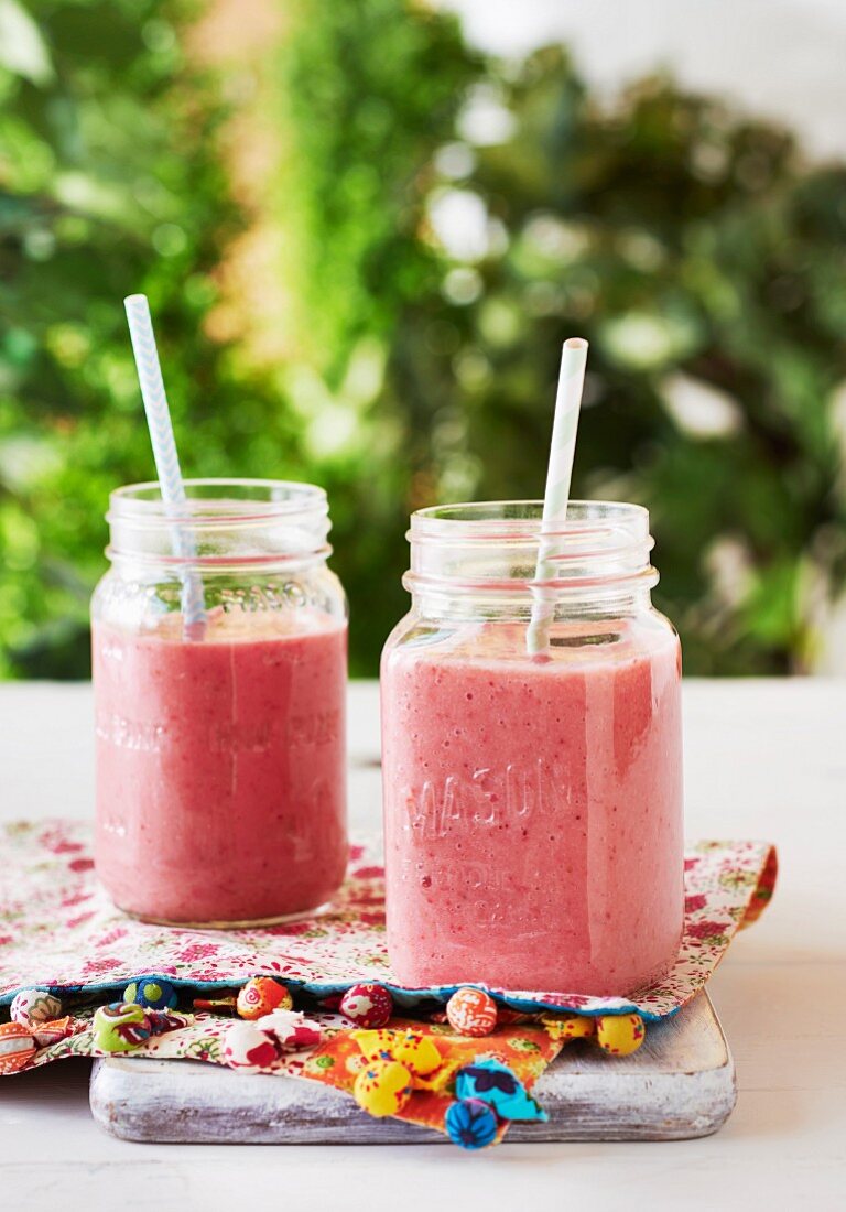 Berry smoothies in scew-top jars with straws