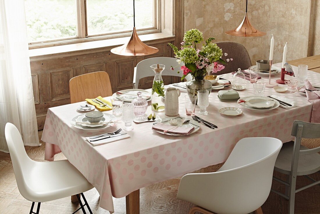 A festively laid table with elegant porcelain on a pastel pink spotted tablecloth