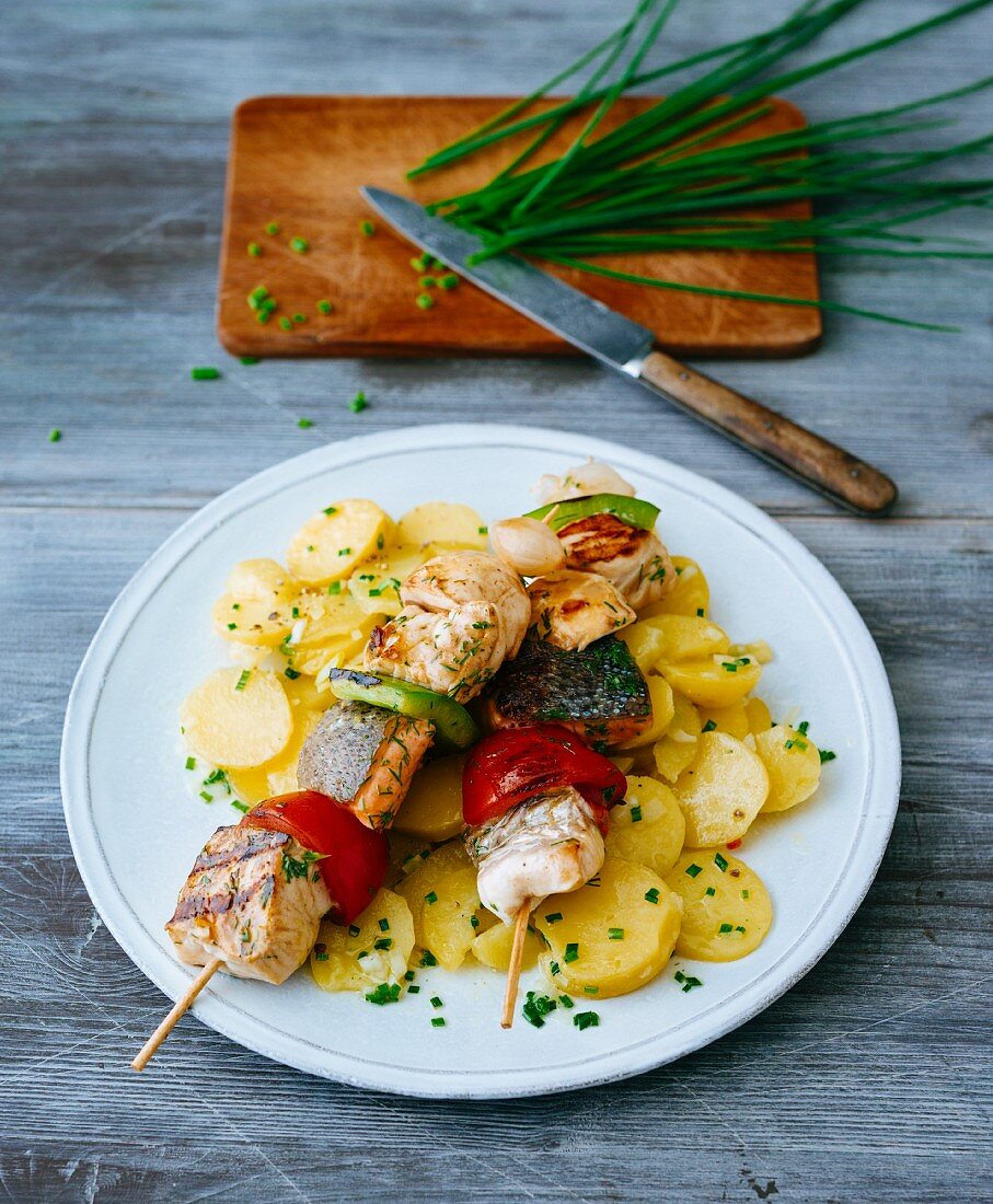 Grilled fish and pepper skewers on a bed of potato salad