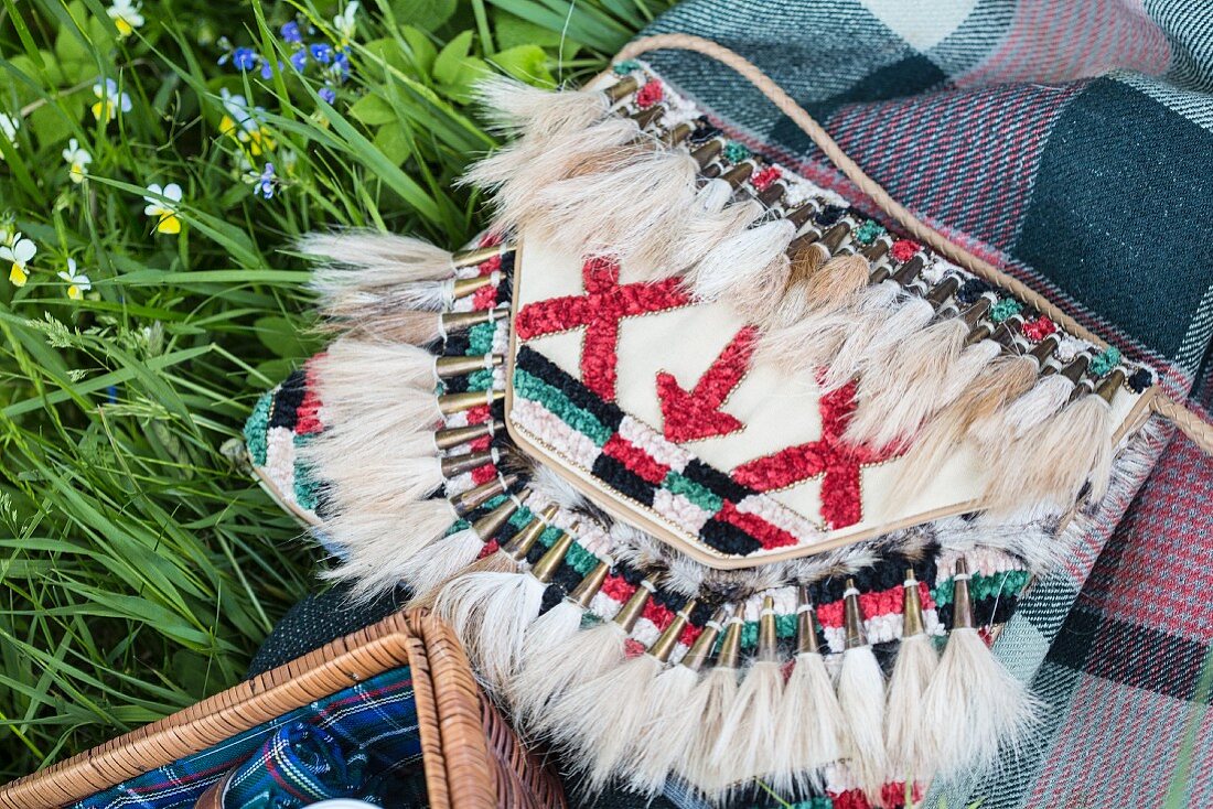 An embroidered handbag with a Native American pattern and fur tassels