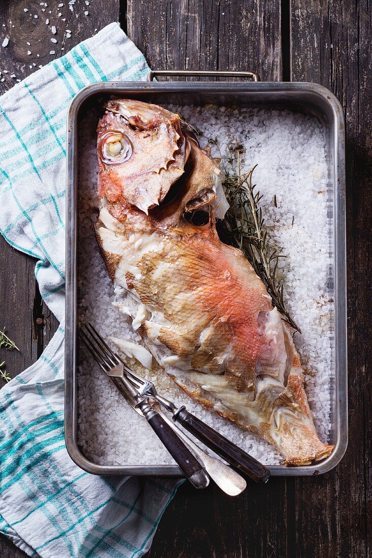Oven-baked sea bass with rosemary on a bed of salt (seen from above)