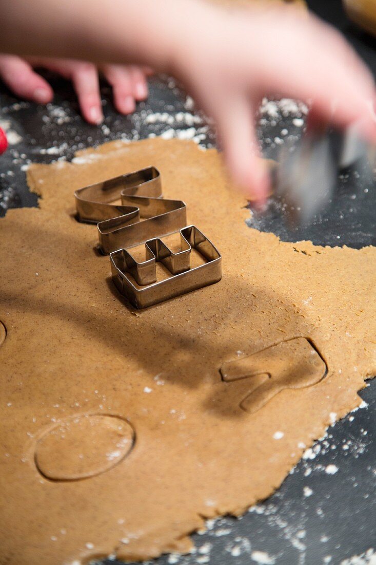 Hands cutting letters out of biscuit dough