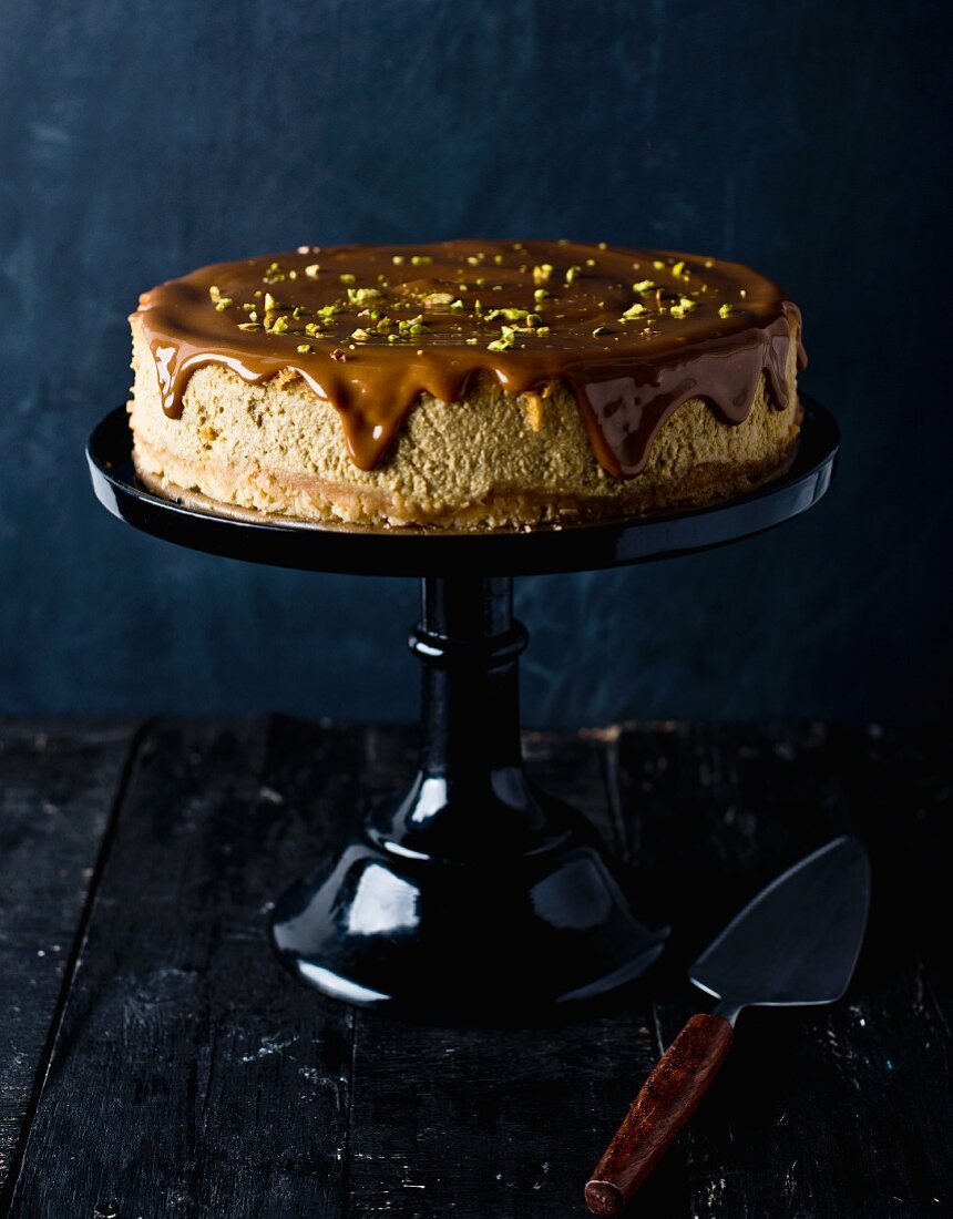 Cheesecake with pistachio nuts and chocolate glaze on a cake stand