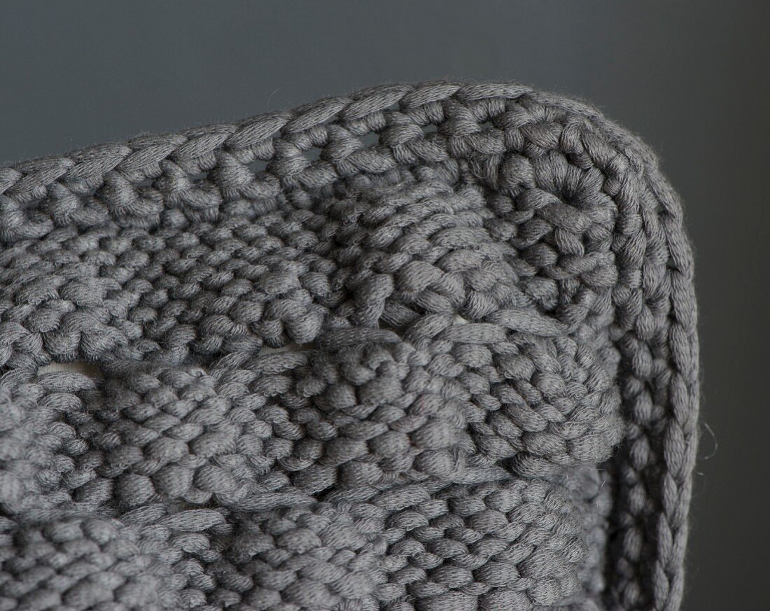 A cushion cover with a knitted now that pattern and a crocheted edge (seen from above)